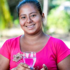 a woman in Mexico holds a glass of water thanks to the safe water project from fftp and water mission
