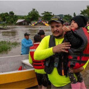 FFTP's rescue team helps a young child across a river with a bridge collapse after Tropical Storm Sara hit Honduras