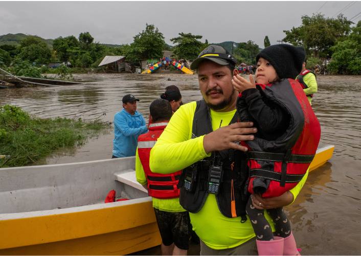 FFTP's rescue team helps a young child across a river with a bridge collapse after Tropical Storm Sara hit Honduras