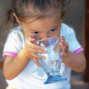 A young girl in Mexico drinks safe water from a glass after FFTP brought water access to her community