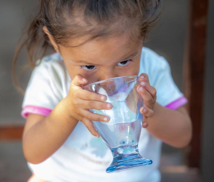 A young girl in Mexico drinks safe water from a glass after FFTP brought water access to her community