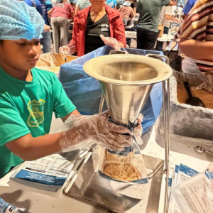 A young boy fills a MannaPack bag at a packing event, like the one to be held on World Food Day