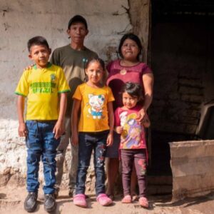 A family in Honduras stands in front of their home, in need of help from year-end fundraising