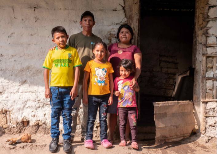 A family in Honduras stands in front of their home, in need of help from year-end fundraising