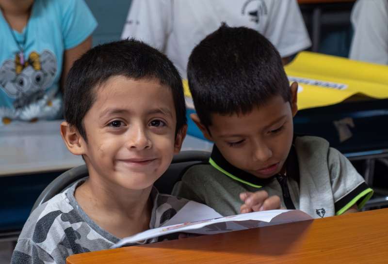 Two young boys sit together at a desk in Bosque de Santa Lucia 