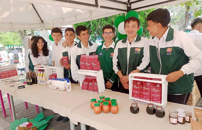 Young individuals standing around a table laden with food products.